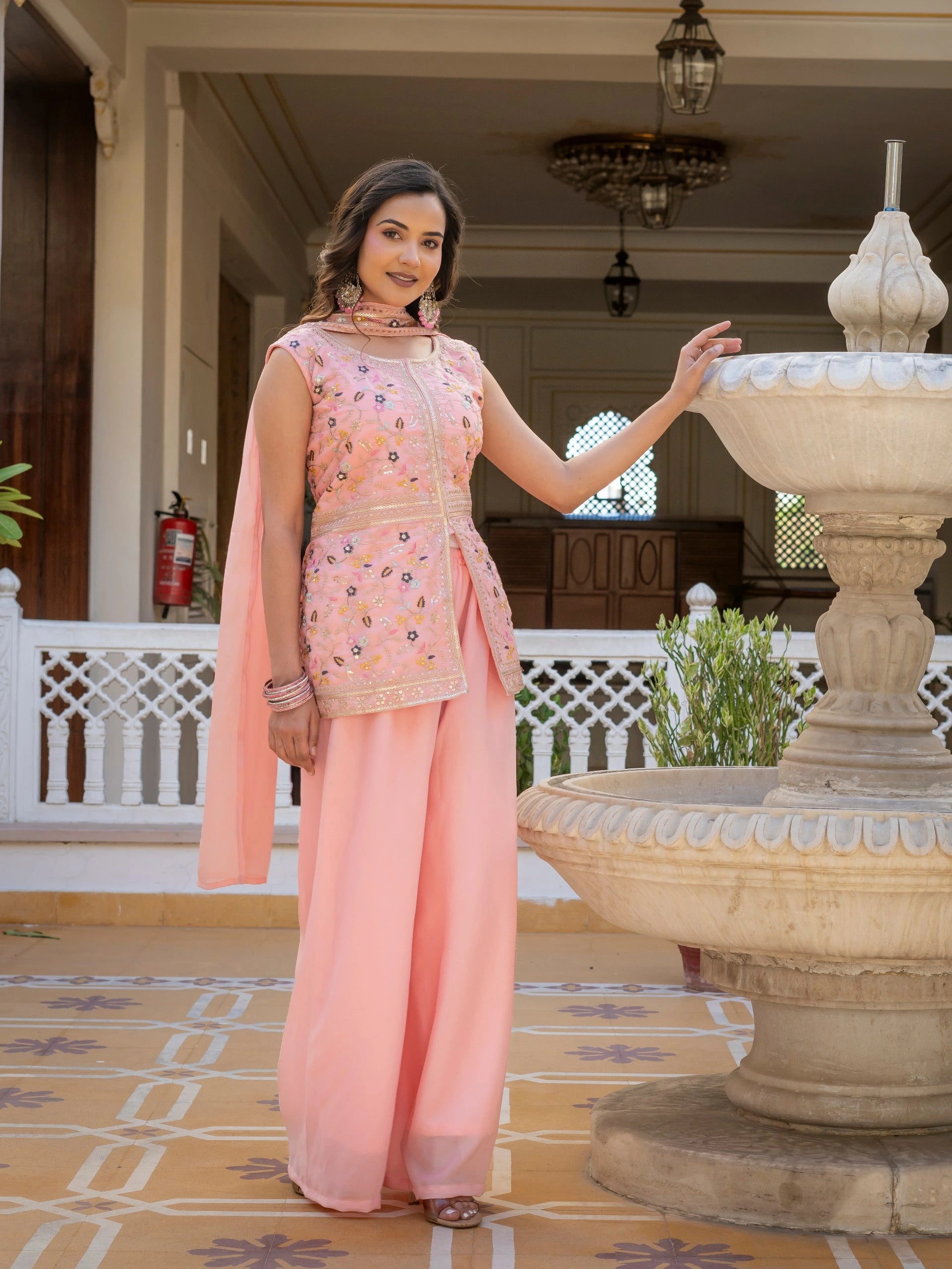 Close-up of light pink georgette fabric highlighting detailed embroidery work.